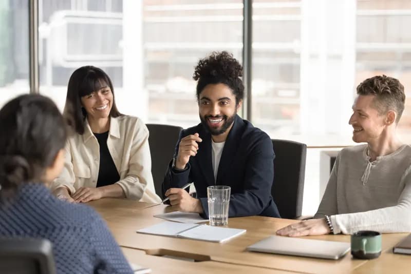 A leader laughing with colleagues around a table