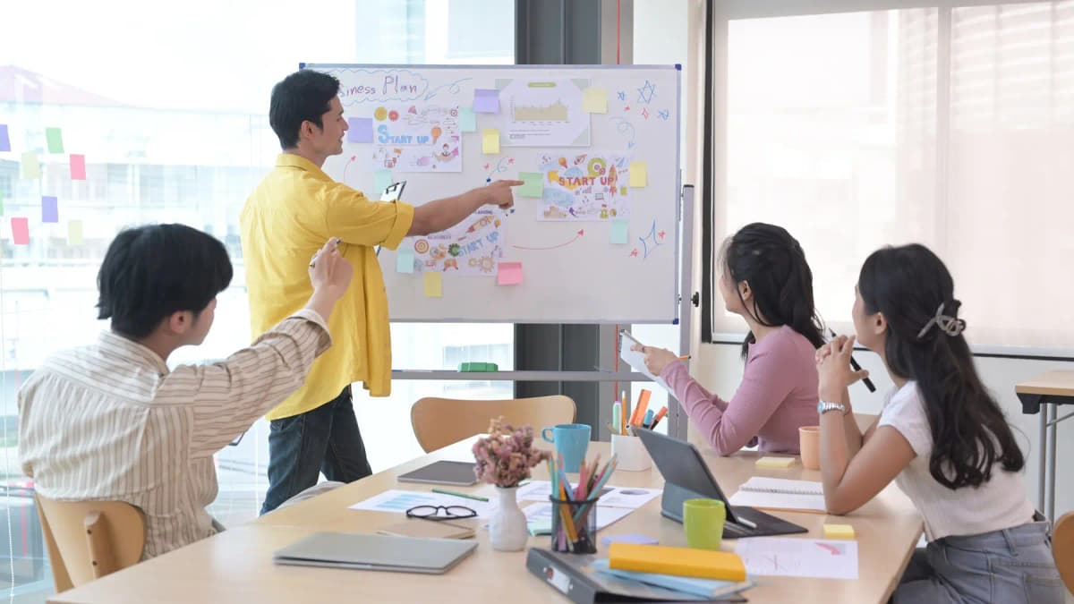 A manager presenting a plan on a whiteboard to a team